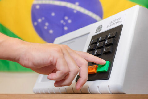 manos activando un sistema de votación con la bandera de brasil