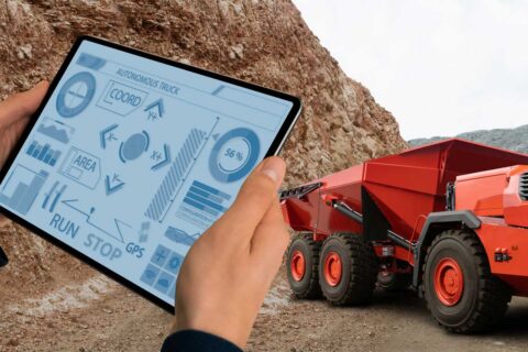 hands holding a tablet, monitoring a mining truck